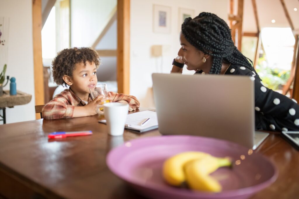 Mother and young son talking across a kitchen table at home, the kind of everyday moment where ABA therapy communication skills are practiced