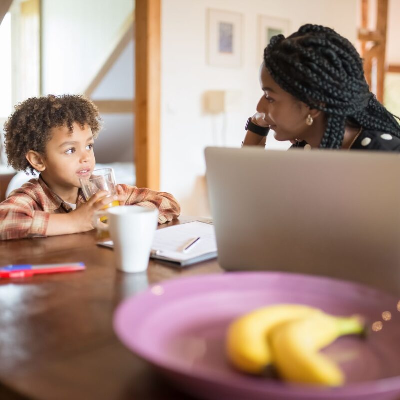 Mother and young son talking across a kitchen table at home, the kind of everyday moment where ABA therapy communication skills are practiced